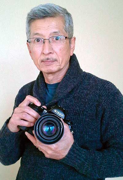Kenji Kawano holds a Nikon camera.