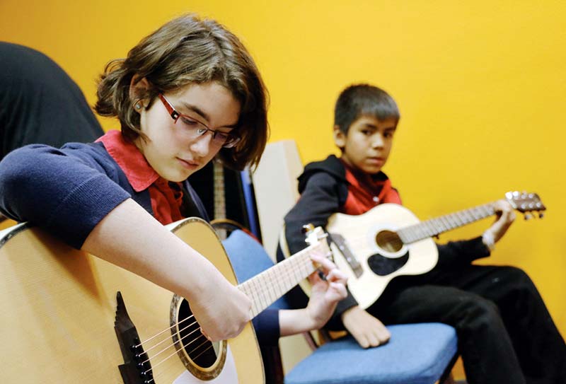 Youth learn to play, tune guitars at music workshop