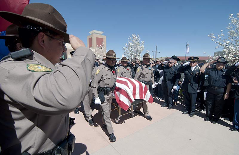 Navajo police officers carry their fallen comrade, officer Alex Yazzie, as another officer salutes on Friday at the Pinon Hills Community Church in Farmington, N.M. (Times photo - Donovan Quintero)