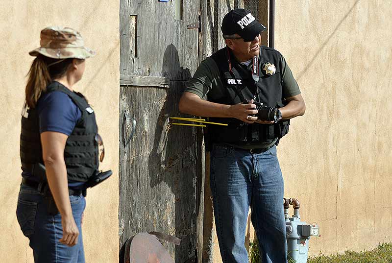Lt. Alvernon Tsosie with the Navajo Nation Criminal Investigations, photographs the crime scene at the home of the alleged shooter on Friday in Fort Defiance. (Times photo - Donovan Quintero)