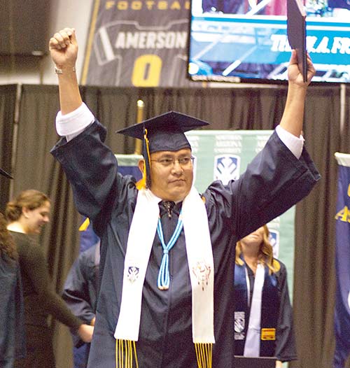 Ruben Redhair proudly raises his arms after being conferred a bachelor’s degree in business management on Friday afternoon during Northern Arizona University’s commencement ceremony at the J. Lawrence Walkup Skydome in Flagstaff. (Times photo – Krista Allen)
