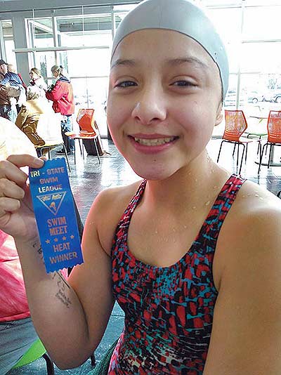 Virginia Snake-Bumann holds up a ribbon from the Tri-State Swim League competition where she won her heat. Snake-Bumann is 13 years old and has been swimming for two years. She said she enjoys swimming because it makes her feel free and weightless. (Courtesy photo)