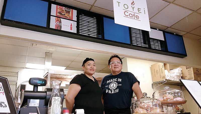 Toyei Café Owner Vault Barrington (right) and Cook Katrina Charley (left) pose behind the counter after the Navajo Times interviewed them last week. (Times photo – Shondiin Silversmith)