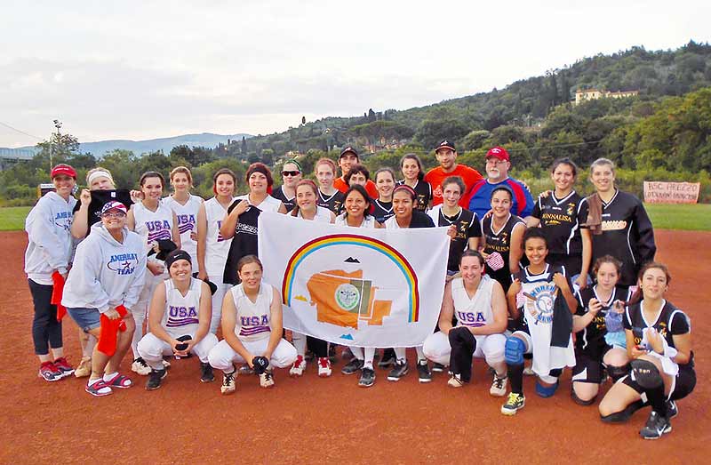 Diné players hold up the Navajo Nation flag after completing a game on June 22 in Italy under the American’s Team program. The team was made up of high school athletes from the Four Corners area that spent a week in Italy touring the area and playing club softball teams. (Courtesy photo)