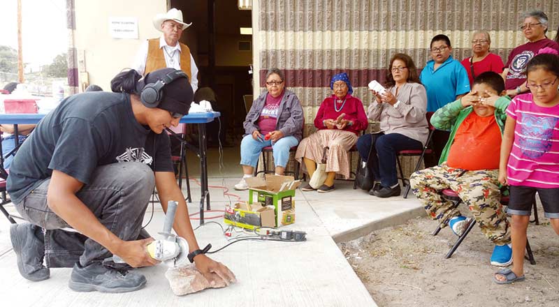 Sculptor Perry Gorman places a piece of stone on the sidewalk to show spectators  what it takes to cut the edges off during the Steamboat Canyon Arts Workshop  last week. (Times photo – Shondiin Silversmith) 