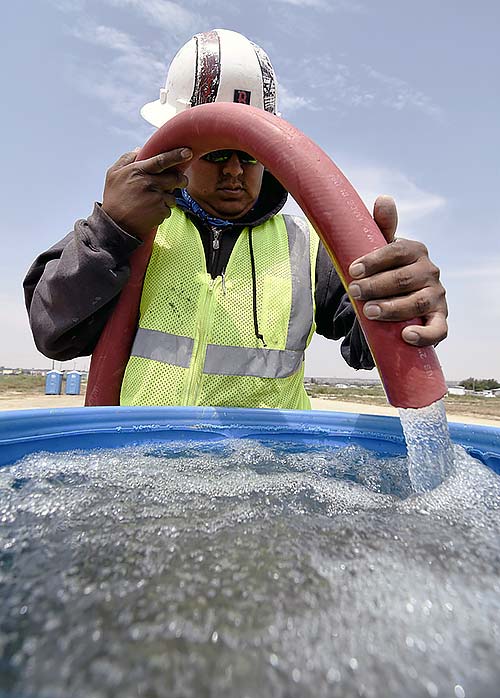 Paul Long Jr with the Navajo Nation Department of Water Resources tops of a 55-gallon barrel with non-potable water Thursday in Shiprock, N.M. Residents living along the San Juan River who've been affected by the Aug. 5 toxic water spill don't have access to the river since the Navajo tribal government shut down access to it until further notice. (Times photo - Donovan Quintero)