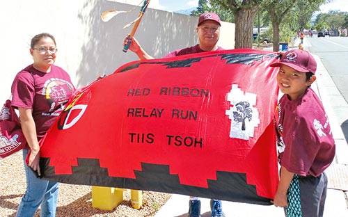 Special to the Times | Colleen Keane Community members from Alamo raise a red ribbon banner at the entrance of the state fairgrounds minutes before runners finish the 24th statewide relay. 