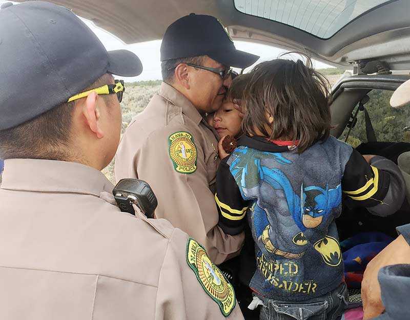 Navajo Times | Donovan Quintero Navajo police officer Chris Holgate, left, watches his partner Philbert Toddy become emotional after the successful search for two young brothers early Wednesday morning in Besbetoh, Ariz. 