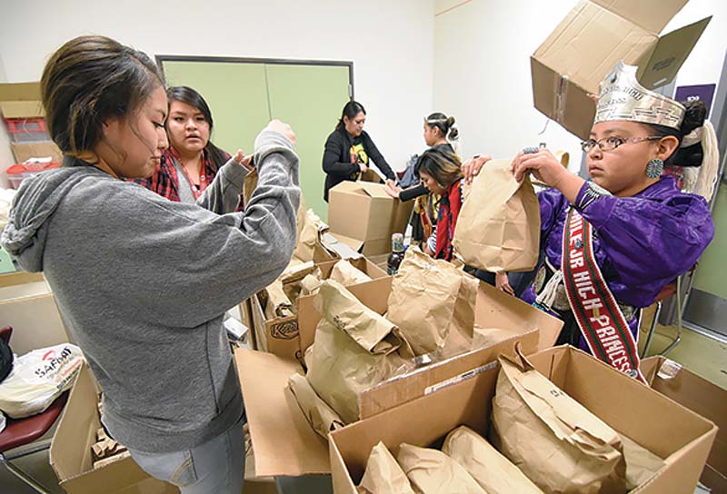 Navajo Times | Donovan Quintero Miss Tsaile Junior High Natiana King, right, and Vanesha Deschine, a freshman at Piedra Vista High School, place bags of frybread into packages they helped prepare for their Farmington Feeding the Homeless event Nov. 25 at the Sycamore Community Center in Farmington. 