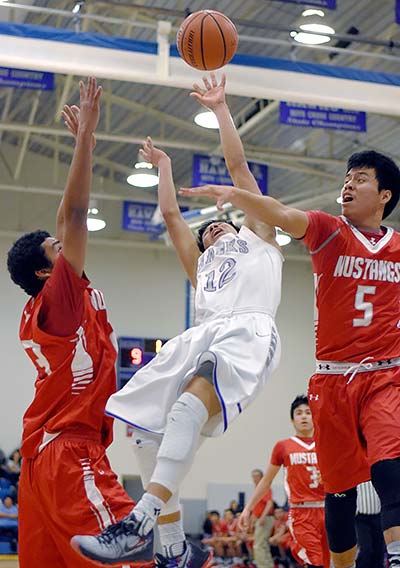 Navajo Times | Donovan Quintero Laguna Acoma’s Jacob Sanchez (12) tosses the ball into the air for the basket as Monument Valley’s Irwin Holiday (5) reaches in for an attempted block Thursday during the Striking Eagle Basketball Invitational in Casa Blanca, N.M. 