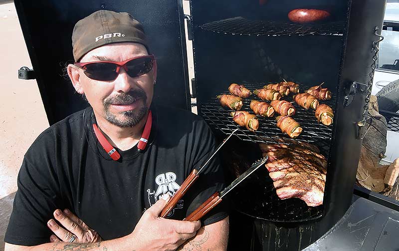 Navajo Times | Donovan Quintero Co-owner of RnR BBQ Robert Slover poses next to his custom-built Texas smoker Friday in Window Rock.