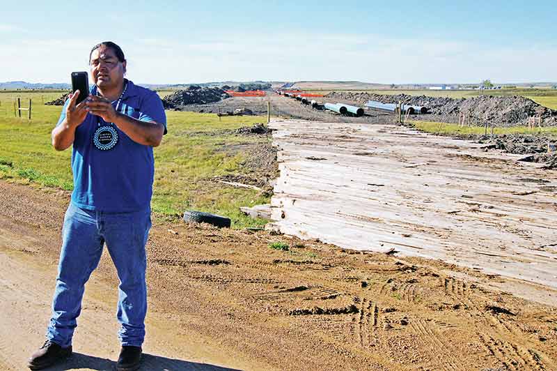 Navajo Times | Christopher S. Pineo Myron Dewey, the Paiute/Shoshone owner of Digital Smoke Signals, uses his cell phone to update Facebook Live viewers, Sept. 17, at a construction site near Standing Rock, N.D., in real time.