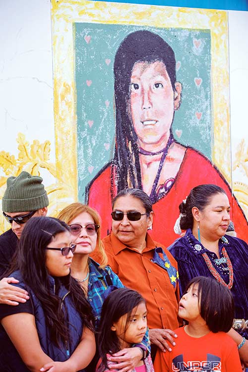 Navajo Times | Adron Gardner A portrait of Ashlynne Mike rises above her family and Council Delegate Amber Crotty during a memorial at the Shiprock fair on Sept. 29.