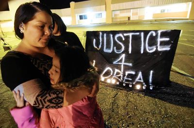 Woman hugging two girls, with black and white sign in background that reads Justice 4 Loreal.