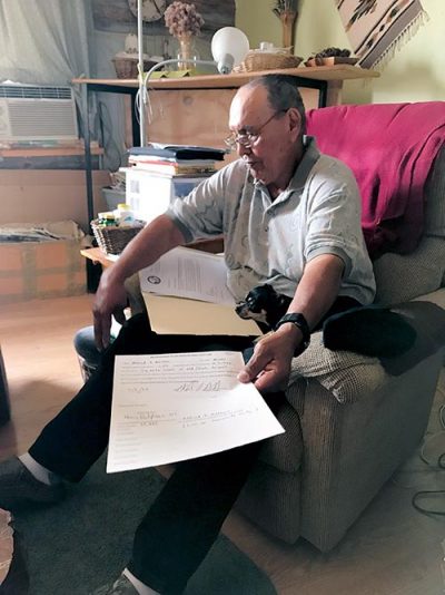 Man sitting in recliner chair looking over government documents.