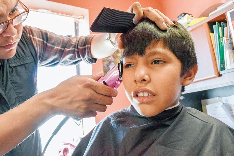 Barber uses pink electric razor to trim boy's bangs