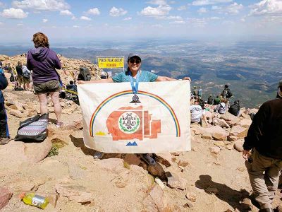 Hikers with unfurled Navajo Nation flag atop Pikes Peak.