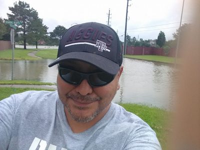 Floodwaters in neighborhood street, and Shawn in foreground.
