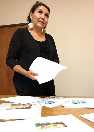Begay stans behind table with printouts and paper in hand.