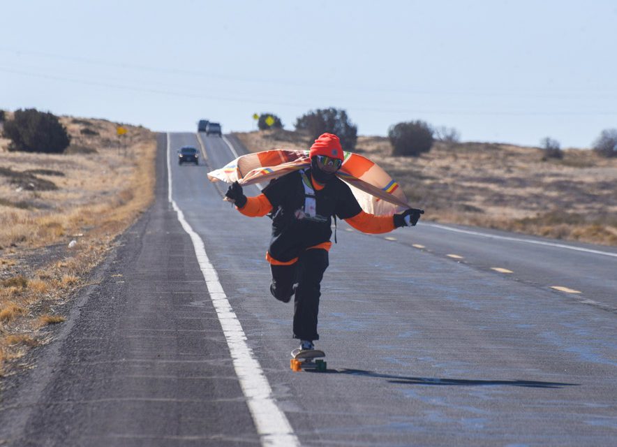 A Navajo Nation flag on his shoulders, he skates the long road toward Shiprock